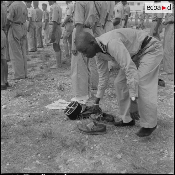 Un officier africain musulman des troupes coloniales se déchausse pour se laver les mains et effectuer ses prières, avant l'embarquement pour le pèlerinage à la Mecque.