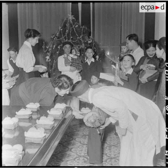 La fille et l'épouse du général Cogny, commandant en chef des FTNV (forces terrestres du Nord-Vietnam), remettent des cadeaux à des enfants vietnamiens lors d'une fête de Noël.