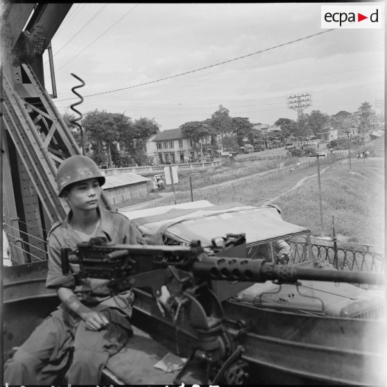 Soldat armé d'une mitrailleuse Browning dans un train passant sur le pont Paul-Doumer (aujourd'hui Long Biên).