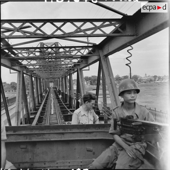 Soldat armé d'une mitrailleuse Browning dans un train passant sur le pont Paul-Doumer (aujourd'hui Long Biên).