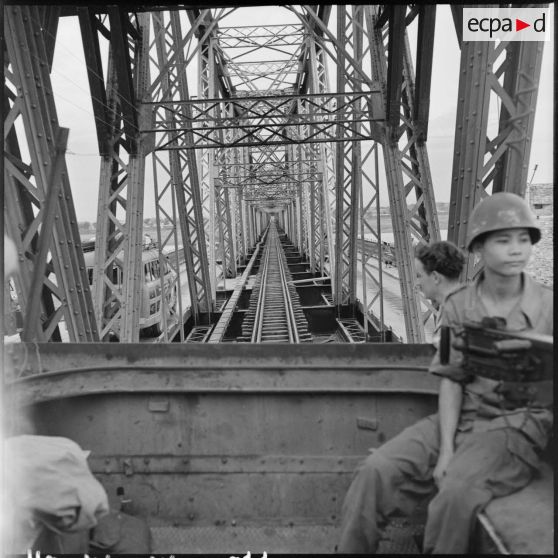 Soldat armé d'une mitrailleuse Browning dans un train passant sur le pont Paul-Doumer (aujourd'hui Long Biên).