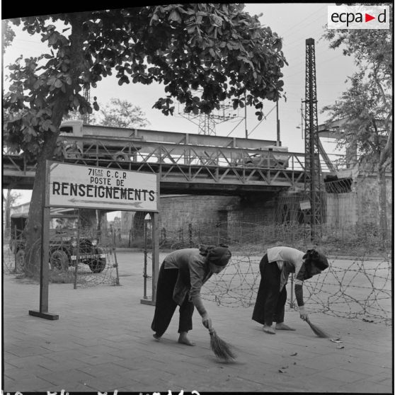 Femmes balayant un trottoir aux abords du poste de renseignements de la 71 CCR (compagnie de circulation routière).