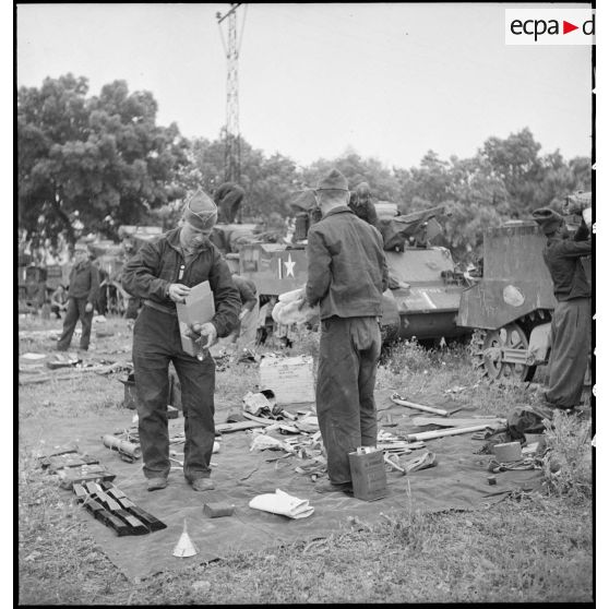 Des chasseurs du 5e RCA (régiment de chasseurs d'Afrique) de la 1re DB (division blindée) inventorient les matériels et lots de bord équipant leurs chars légers Stuart M5 A1 dans un champ en bordure d'une route menant à Blida.