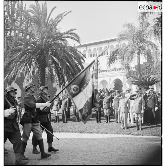 A l'issue de la remise des insignes de grand-croix de la Légion d'honneur au général Dwight Eisenhower, commandant en chef des forces alliées en Afrique, par le général d'armée Henri Giraud, commandant en chef civil et militaire, les autorités assistent à un défilé de troupes de l'armée d'Afrique, ici le drapeau du 1er RZ (régiment de zouaves) et sa garde.