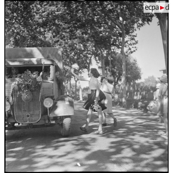 Des jeunes filles lancent des fleurs sur un camion Renault du 65e RAA (régiment d'artillerie d'Afrique), de retour à Blida après avoir participé à la campagne de Tunisie.