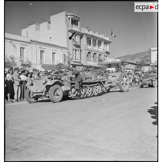 Un semi-chenillé allemand SdKfz-11 tractant un canon de 75 mm, modèle 1897, pris à l'ennemi par le 65e RAA (régiment d'artillerie d'Afrique) pendant la campagne de Tunisie, défile dans une rue de Blida.