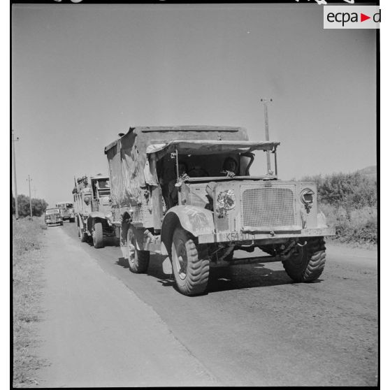 Une colonne de véhicules du 65e RAA (régiment d'artillerie d'Afrique), de retour de la campagne de Tunisie, circule sur une route menant à Blida. Au premier plan, un véhicule d'origine britannique.