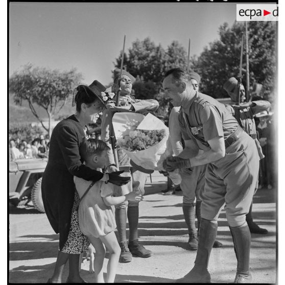 De retour de la campagne de Tunisie, le colonel Dumas, commandant le 65e RAA (régiment d'artillerie d'Afrique), reçoit des fleurs d'un jeune garçon à Blida.