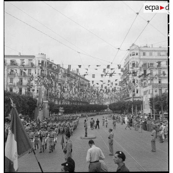 Défilé de la garde mobile lors du 14 juillet 1943 dans une rue pavoisée d'Alger.