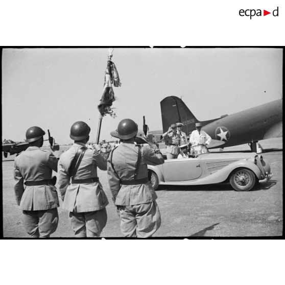 Le général de division Charles Mast, résident général de France en Tunisie, qui quitte l'aérodrome d'El-Aouina de Tunis à bord d'une voiture Delahaye en compagnie de monsieur Lafont, salue un drapeau et sa garde.