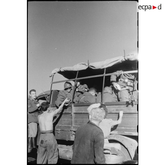 Des tirailleurs marocains, embarqués à bord de camions de l'armée italienne, sont salués par la population corse.