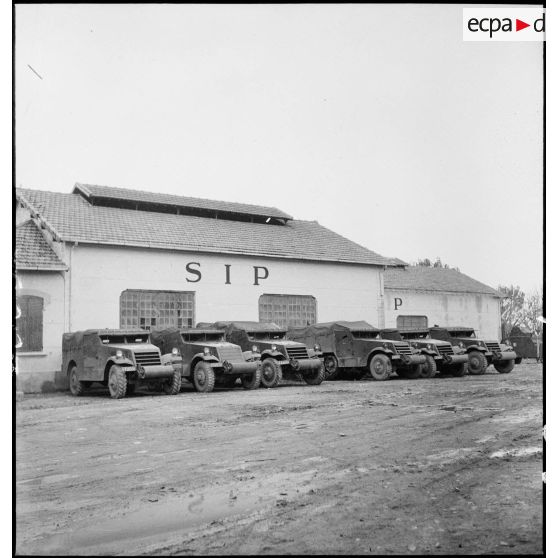 Des scout-car M3A1 et des half-track M3 sont parqués devant un des garages de l'école des élèves aspirants ou CIEO (Centre d'instruction des élèves officiers) de Cherchell à la caserne Dubourdieu.