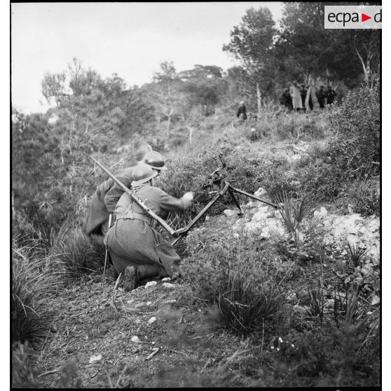 Au cours d'un exercice d'approche à l'école des élèves aspirants ou CIEO (Centre d'instruction des élèves officiers) de Cherchell, des élèves installent une mitrailleuse Hotchkiss modèle 1914 sur son affût, sous les yeux d'un instructeur.