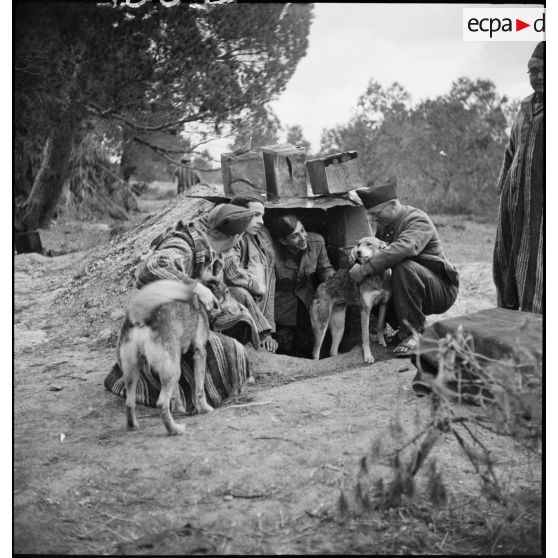 Photographie de groupe de supplétifs du 1er GSM (groupe de supplétifs marocains) de la 1re DMM (division de marche du Maroc) devant un abri dans le campement de l'unité.