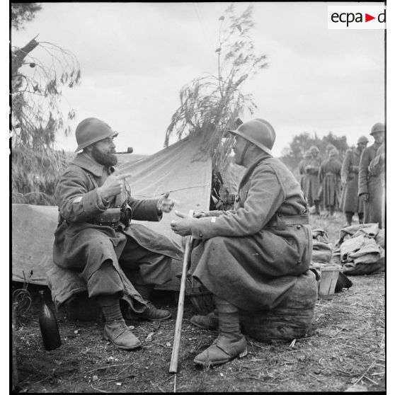 Un sergent-chef et un lieutenant du 7e RTA (régiment de tirailleurs algériens) de la DMC (division de marche de Constantine) discutent devant une tente dans le campement de l'unité, dans le secteur de Maktar.