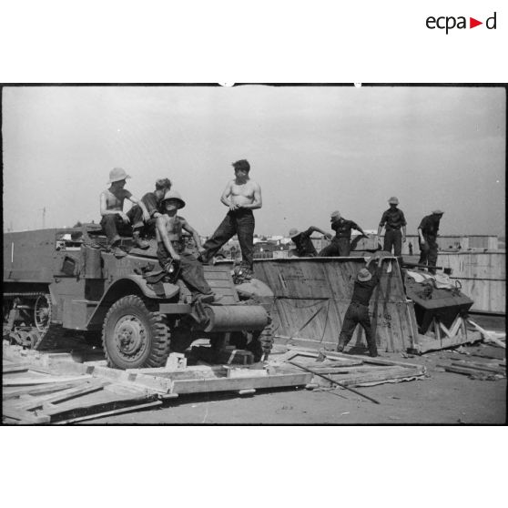 Une automitrailleuse M8 (ou light armored car) et un half-track M3 sont sortis de leur caisse de transport par des équipes de montage sur le port de Casablanca.