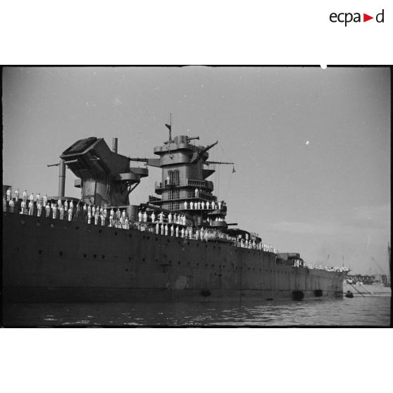 L'équipage du cuirassé Jean Bart est à la bande sur le pont du navire dans le port de Casablanca à l'occasion d'une visite d'inspection du général d'armée Henri Giraud, commandant en chef civil et militaire et coprésident du CFLN (comité français de la Libération nationale).