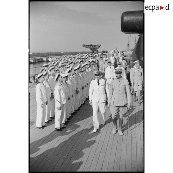 Au cours d'une visite d'inspection à bord du cuirassé Jean Bart, le général d'armée Henri Giraud, commandant en chef civil et militaire et coprésident du CFLN (comité français de la Libération nationale), et le capitaine de vaisseau Charles de la Fournière, commandant le bâtiment, passent l'équipage en revue.