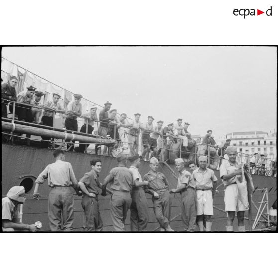 Des tirailleurs du 1er régiment de tirailleurs marocains (RTM) et des marins patientent sur un quai du port d'Alger avant l'appareillage de navires pour la Corse.