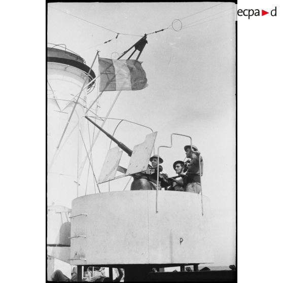 Des marins, servants d'un canon de défense antiaérienne, sont à leur poste de combat à bord d'un des navires d'escorte du convoi à destination de la Corse.