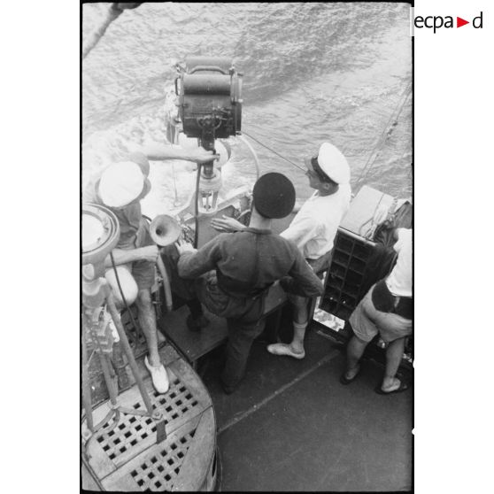 Marins à leur poste d'observation sur la passerelle extérieure d'un des bâtiments du convoi. A gauche, une lanterne Scott et une alidade de navigation.