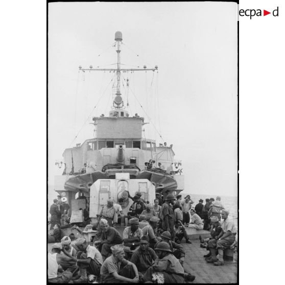 Des tirailleurs du 1er régiment de tirailleurs marocains (RTM) sont rassemblés sur le pont  avant d'un navire à destination de la Corse.