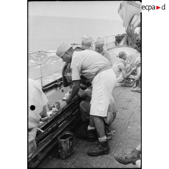 Des tirailleurs du 1er RTM (régiment de tirailleurs marocains) se restaurent sur le pont d'un torpilleur ou contre-torpilleur naviguant vers la Corse.