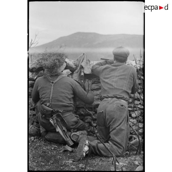 Un tirailleur marocain et un résistant corse sont postés derrière un mur de pierres dans le maquis, dans le secteur du col de San Stefano.