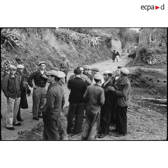 Des habitants du village de Patrimonio libéré discutent avec le lieutenant Albert Plécy, officier de presse et photographe du service cinématographique de l'Armée (SCA).