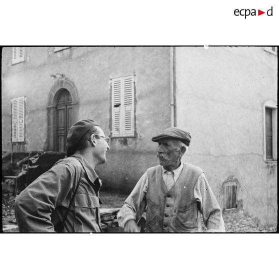 Un habitant du village de Patrimonio libéré discute avec le lieutenant Albert Plécy, officier de presse et photographe du service cinématographique de l'Armée (SCA).