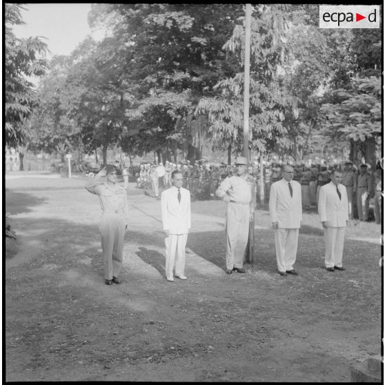 Le général de Castries, M. le Gouverneur du Nord-Vietnam, le général Cogny, M. Bordaz et M. Compain devant un monument aux morts dans un square.