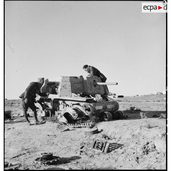 Deux soldats français examinent l'épave d'un canon automoteur Semovente L40 47/32 de l'armée italienne dans le désert tunisien.