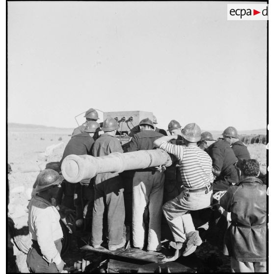 Des canonniers marins, d'une batterie mobile de 90 de marine, utilisent le télémètre pour ajuster les tirs d'un canon de 90 mm, modèle 1939 Schneider antiaérien.