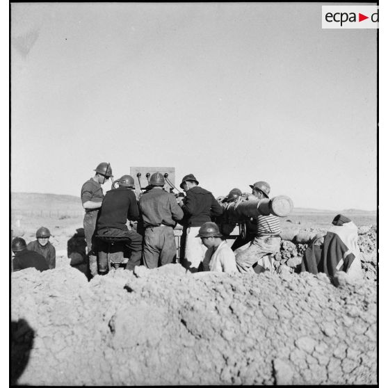 Des canonniers marins, d'une batterie mobile de 90 de marine, utilisent le télémètre pour ajuster les tirs d'un canon de 90 mm, modèle 1939 Schneider antiaérien.