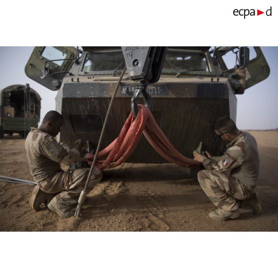 Mise en place du dispositif de levage sur un VAB par des mécaniciens lors d'une intervention technique dans le désert.