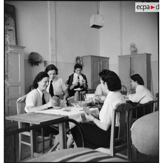 Vie courante pour des élèves de l'école des transmissions des personnels féminins de l'armée de l'Air dans leur chambrée : tricot et jeu de cartes.