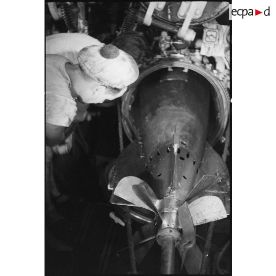 Dans la chambre des torpilles du sous-marin Casabianca, des sous-mariniers chargent une torpille de 550 ou de 400 mm dans un des tubes lance-torpilles.