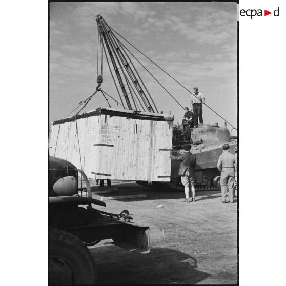 Déchargement d'une caisse de matériel américain, destiné aux troupes françaises, par une grue improvisée montée sur un char Sherman dans le port de Casablanca.