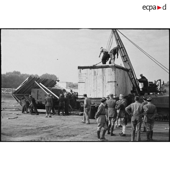 Déchargement d'une caisse de matériel américain, destiné aux troupes françaises, par une grue improvisée montée sur un char Sherman dans le port de Casablanca.