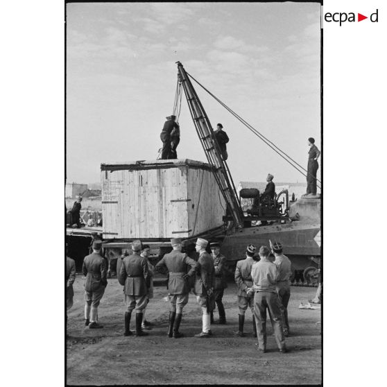 Déchargement d'une caisse de matériel américain, destiné aux troupes françaises, par une grue improvisée montée sur un char Sherman dans le port de Casablanca.