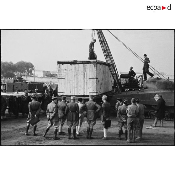 Déchargement d'une caisse de matériel américain, destiné aux troupes françaises, par une grue improvisée montée sur un char Sherman dans le port de Casablanca.