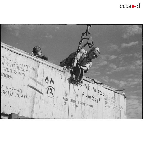 Des prisonniers italiens réquisitionnés déchargent une caisse de matériel américain destiné aux troupes françaises sur le port de Casablanca.