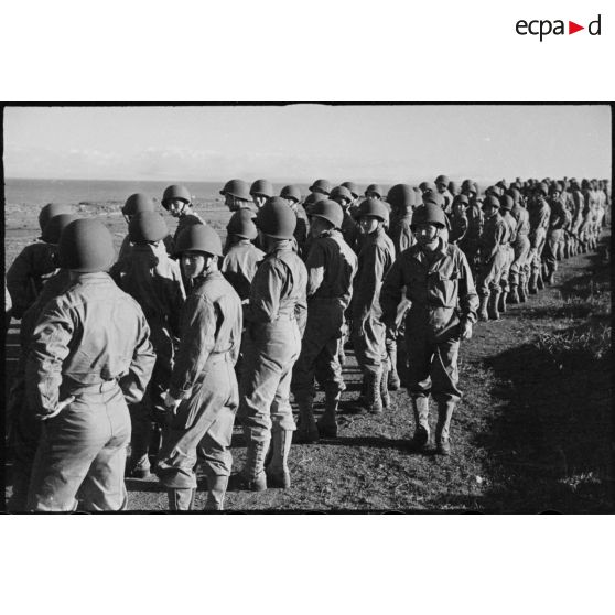 Rassemblement sur les rangs de soldats de la 2e division blindée (2e DB), équipés de tenues américaines, lors d'une inspection de la division.