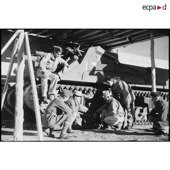 Au centre d'instruction divisionnaire, un sergent instructeur américain donne des détails techniques concernant les galets de roulement d'un obusier automoteur de 105 mm Howitzer Motor Carriage M7 à des soldats de la 2e division blindée (2e DB).