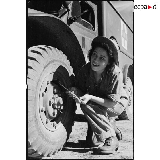 Vérification de la pression d'un pneu d'une ambulance Dodge T215 par une volontaire féminine conductrice à la 521e compagnie sanitaire.