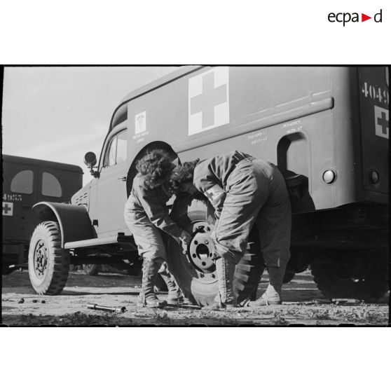 Changement d'une roue d'ambulance Dodge T215 par deux volontaires féminines conductrices à la 521e compagnie sanitaire.