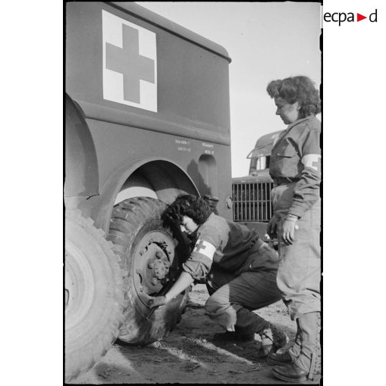 Changement d'une roue d'ambulance Dodge T215 par deux volontaires féminines conductrices à la 521e compagnie sanitaire.