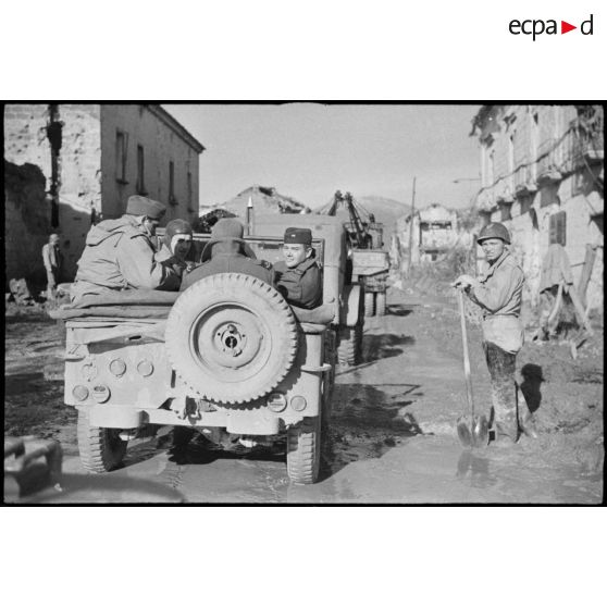 Des correspondants de guerre américains traversent un village.