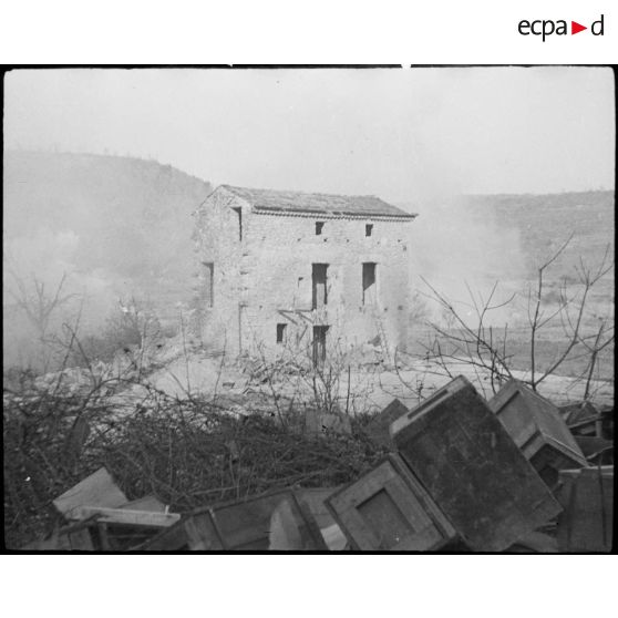 Une maison en ruines au milieu de la fumée et des bombardements.