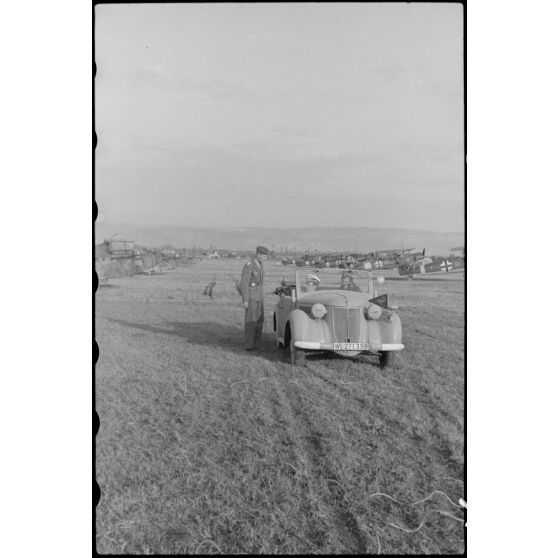 A bord d'un cabriolet Auto-Union, un capitaine (peut-être l'Hauptmann Joseph Karl) Gruppenkommandeure III./LLG.1 inspecte l'aérodrome de Valence-Chabeuil (Drôme) avant une mission.